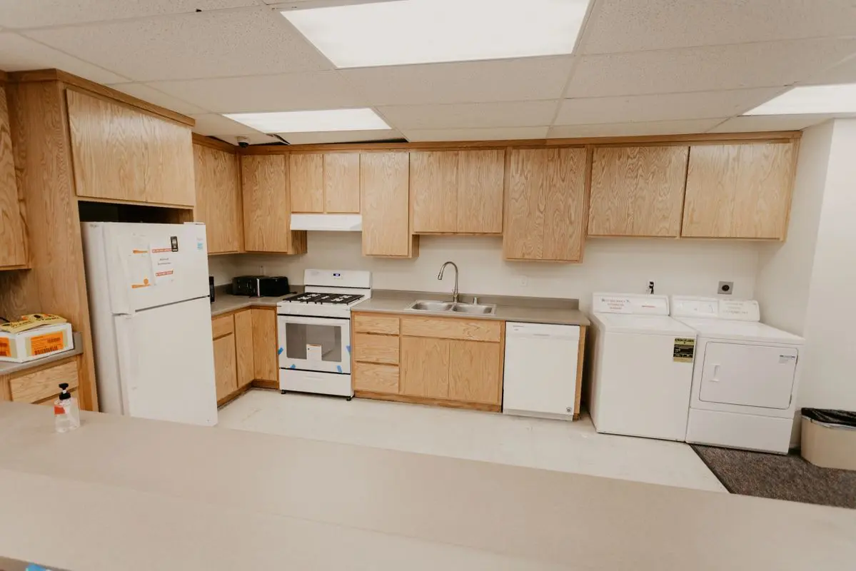 A kitchen with a refrigerator, microwave, and washer and dryer.