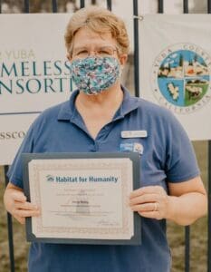 A woman with a mask holding a certificate for homeless transportation.