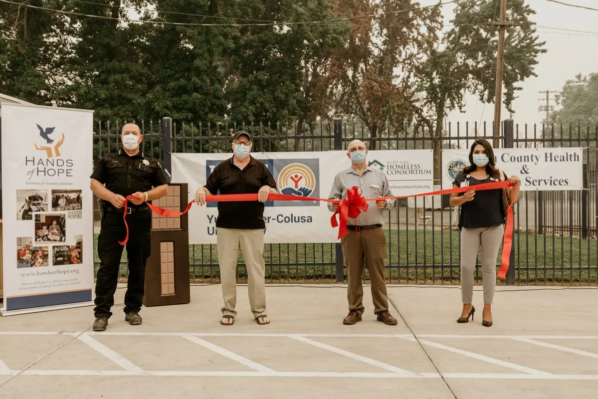 A group of people standing in front of a fence with a ribbon.