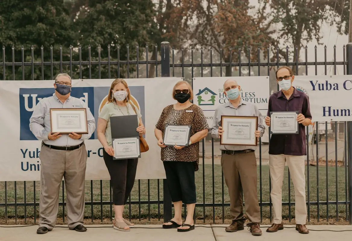 A group of people holding certificates in front of a fence.