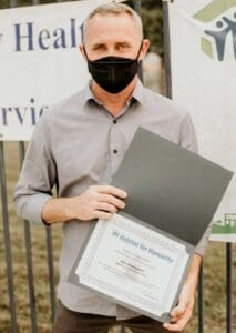 A man with a mask holding a certificate.
