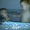 Two babies in a crib playing with a dog.