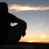 A man sitting on a bench watching the sunset.