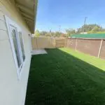 A backyard with grass and a fence.