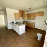 An empty kitchen with wood floors and cabinets.