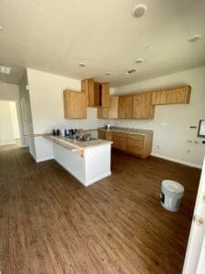 An empty kitchen with wood floors and cabinets.