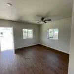 Empty living room with hardwood floors and a ceiling fan.