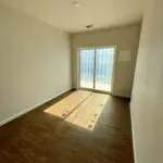 An empty room with hardwood floors and sliding glass doors.