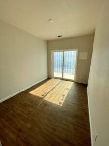 An empty room with hardwood floors and sliding glass doors.