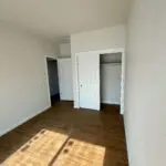 An empty room with hardwood floors and closets.