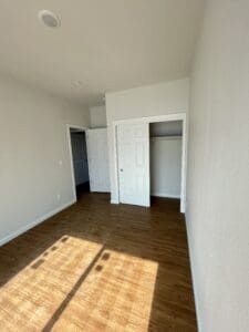 An empty room with hardwood floors and closets.