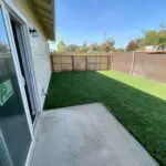 A backyard with artificial grass and a sliding glass door.