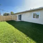 A backyard with grass and a fence.