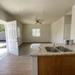 An empty kitchen with wood floors and a sink.