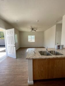 An empty kitchen with wood floors and a sink.