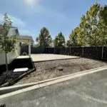 An empty lot with a driveway and a fence.