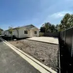 An empty lot with a house and a fence.