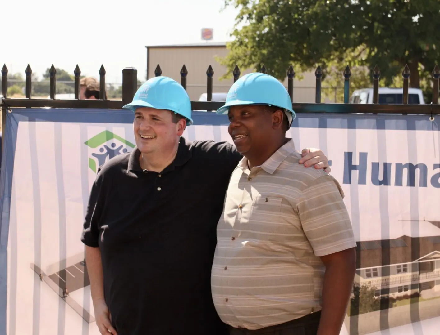 Two men in hard hats standing next to each other.