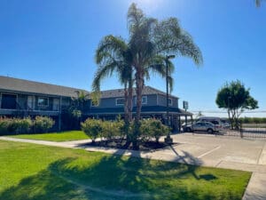 The front of a motel with palm trees and a parking lot.