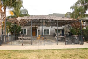 A metal gazebo with a table and chairs in front of a building.