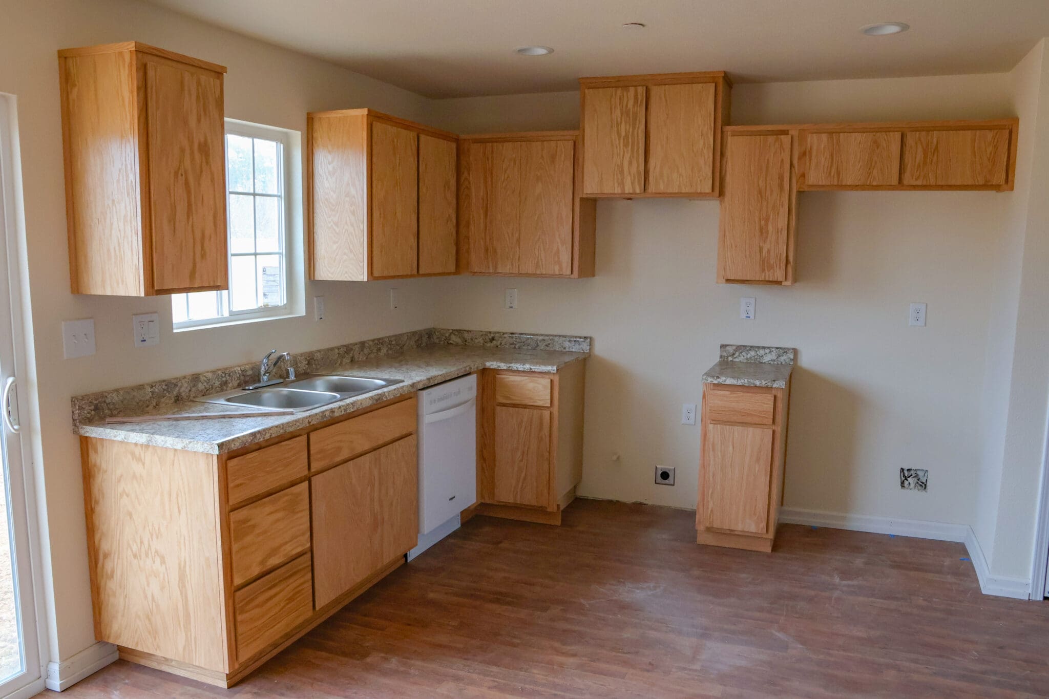 An empty kitchen with wood cabinets and a stove.