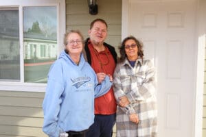 Three people standing in front of a house.