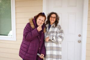 Two women standing in front of a house.