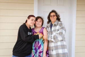 Three women standing in front of a house.