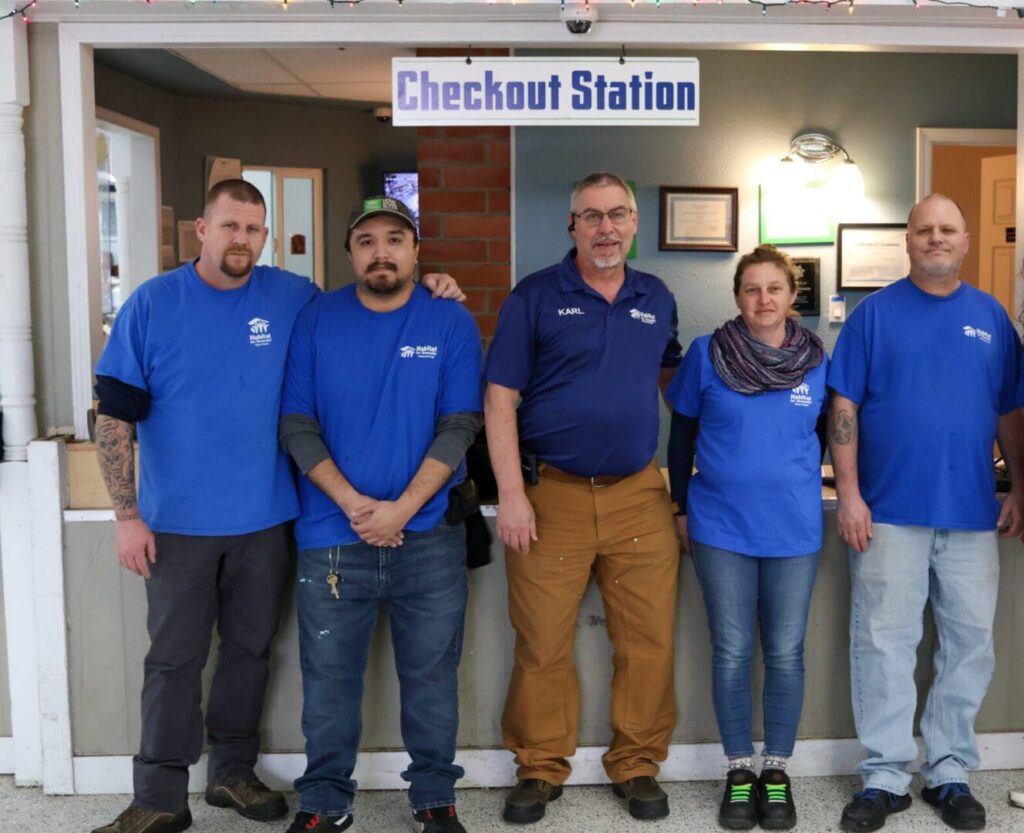 A group of people in blue shirts standing in front of a store.