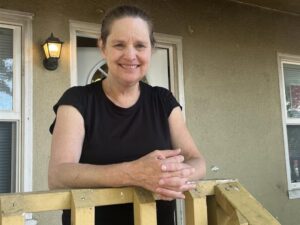 Margaret Mix stands on the front porch of her new home